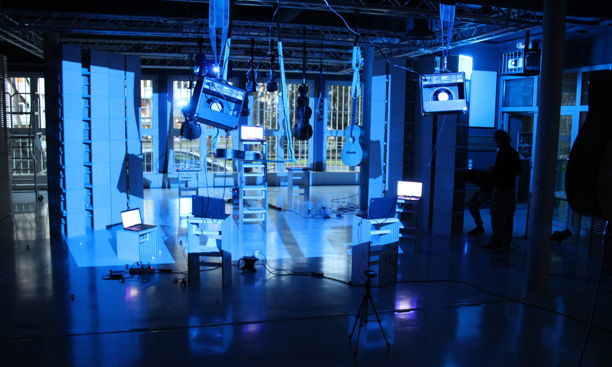 Eine Zoomsitzung mit Rochus Aust, dem Artist der Residence ,Digitale Irritationen‘. Instrumente hängen von der Decke und sind blau beläuchtet